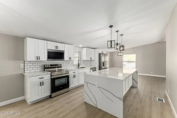 a kitchen with stainless steel appliances a white stove top oven a sink dishwasher and a refrigerator with wooden floor