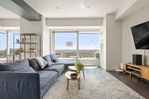 a living room with furniture a flat screen tv and a floor to ceiling window