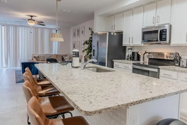 a kitchen with stainless steel appliances granite countertop a sink a stove a refrigerator with a dining table and chairs