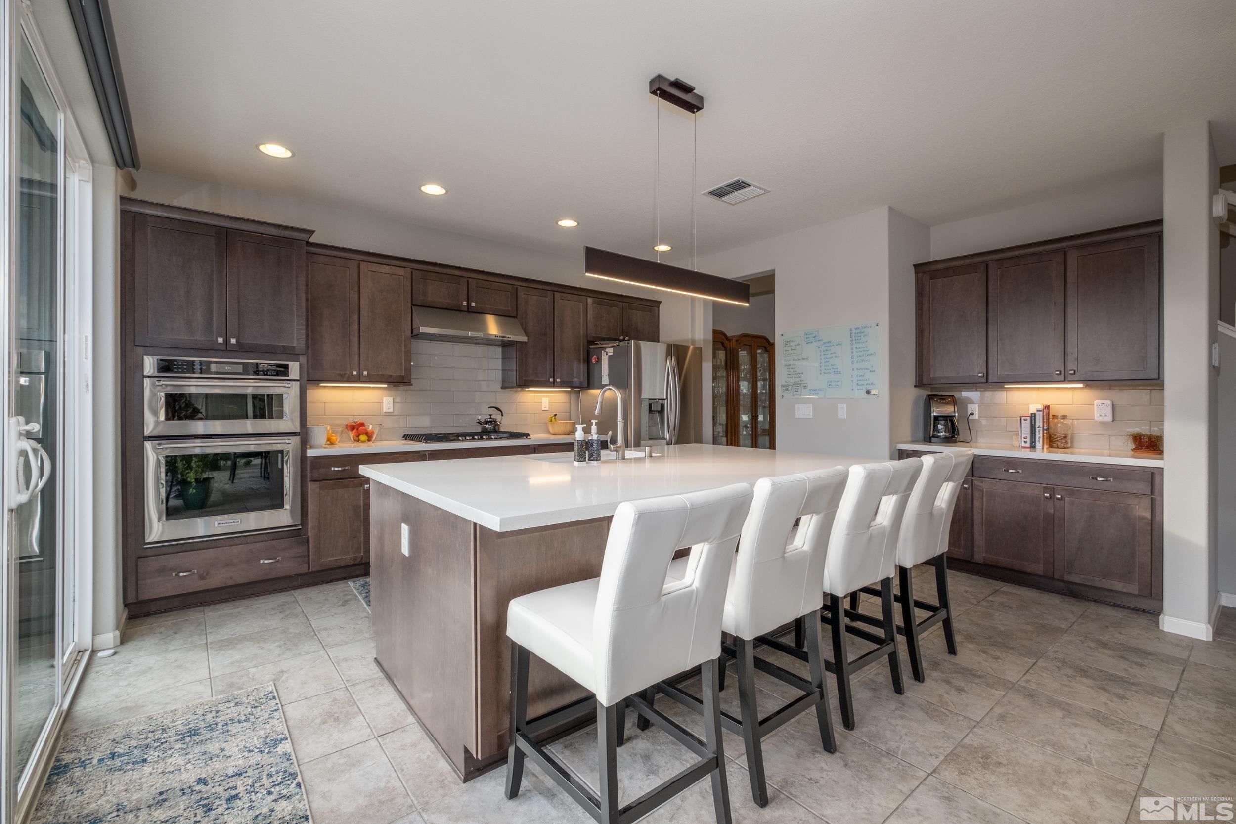 2960 Ethelinda Way Reno, NV 89521 - Photo 10 of 40 a kitchen with kitchen island granite countertop wooden cabinets and center island with chairs