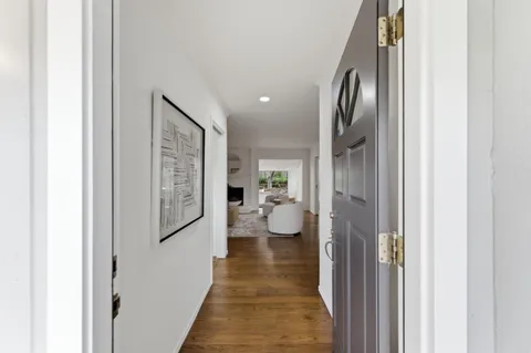 a view of a hallway with wooden floor and a living room