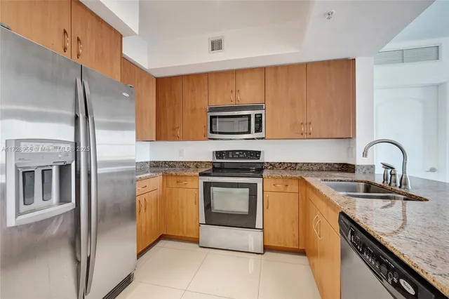 a kitchen with stainless steel appliances granite countertop a sink refrigerator and cabinets