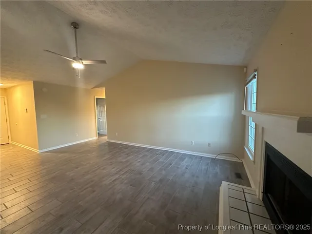 a view of empty room with wooden floor and fireplace