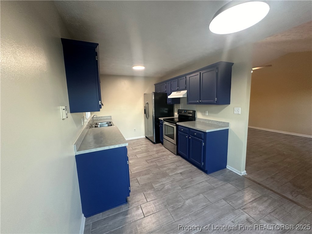 8249 Rockfish Road Raeford, NC 28376 - Photo 4 of 12 a kitchen with stainless steel appliances granite countertop a sink stove and wooden cabinets