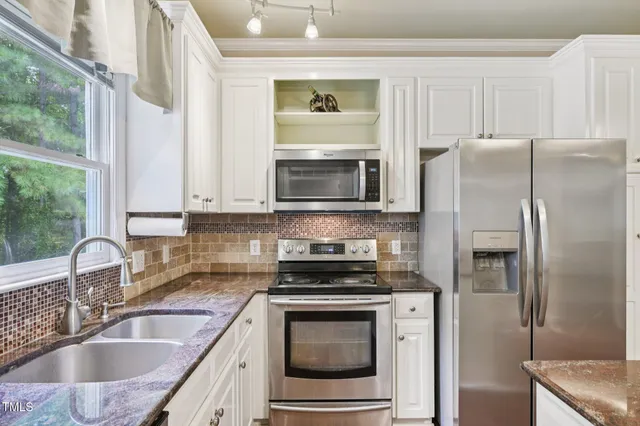a kitchen with granite countertop a refrigerator stove and sink