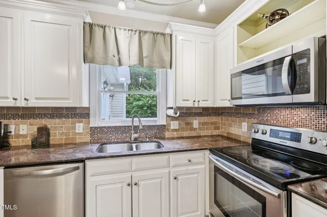 a kitchen with stainless steel appliances granite countertop a sink a stove and cabinets