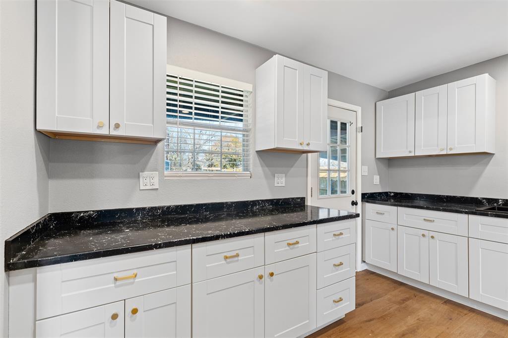 902 Turner Street Cleburne, TX 76033 - Photo 13 of 33 a kitchen with granite countertop white cabinets white appliances and a sink
