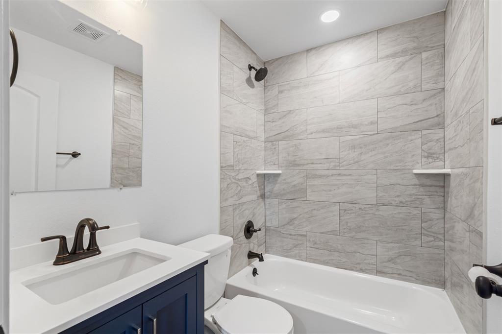 902 Turner Street Cleburne, TX 76033 - Photo 24 of 33 a bathroom with a bathtub shower sink vanity mirror and toilet