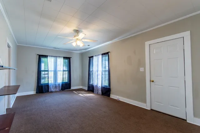 a view of a livingroom with a chandelier fan and windows