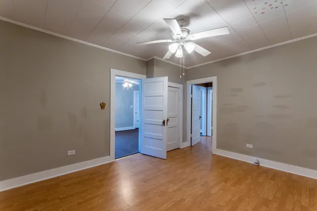 an empty room with wooden floor and chandelier fan