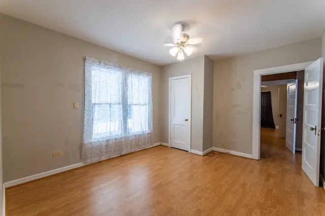 an empty room with chandelier fan and windows