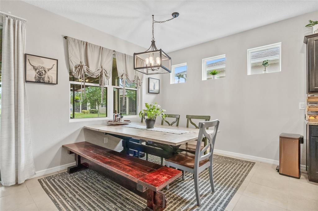 13675 Paddington Way Spring Hill, FL 34609 - Photo 11 of 36 a dining room with wooden floor a chandelier a wooden table and chairs