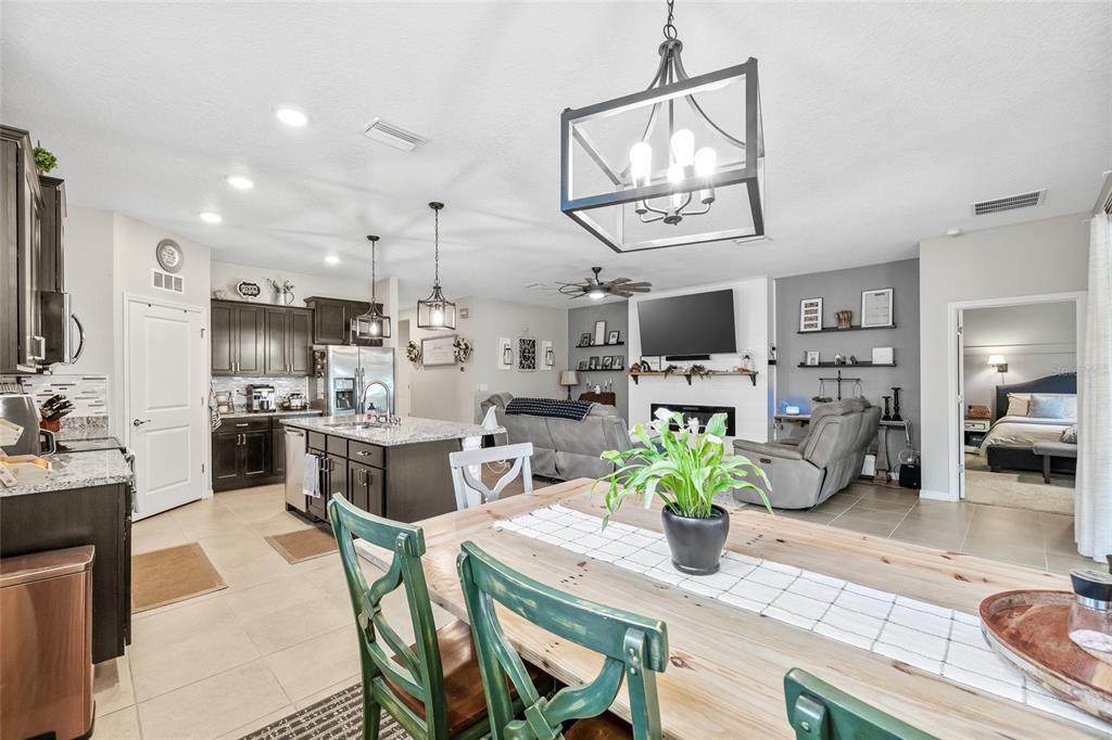 13675 Paddington Way Spring Hill, FL 34609 - Photo 12 of 36 a dining room with stainless steel appliances kitchen island granite countertop furniture a rug kitchen view and a chandelier
