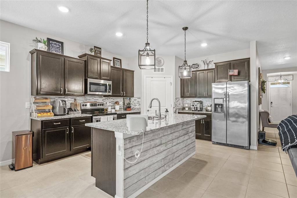 13675 Paddington Way Spring Hill, FL 34609 - Photo 13 of 36 a kitchen with stainless steel appliances kitchen island granite countertop a refrigerator stove and sink