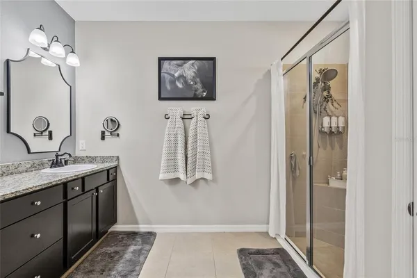 a bathroom with a granite countertop sink a mirror and a shower
