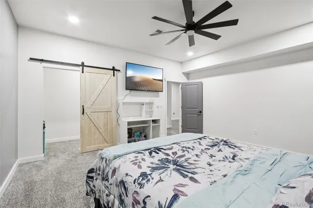 a living room with a bed furniture and ceiling fan