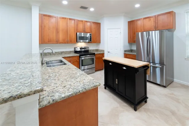 a kitchen with stainless steel appliances granite countertop a stove a sink and a refrigerator