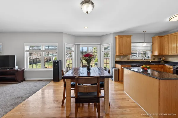 a kitchen with stainless steel appliances granite countertop a stove top oven a sink dishwasher a dining table and chairs with wooden floor