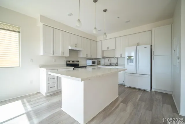 a kitchen with kitchen island a white counter top space cabinets and stainless steel appliances