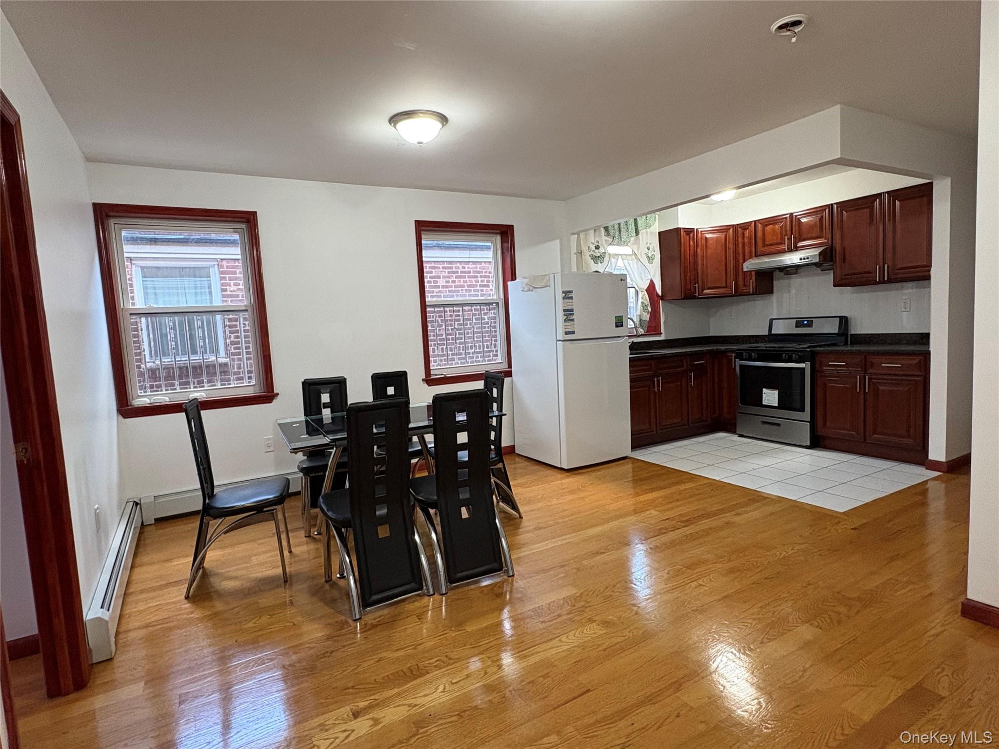 61-40 148th Street, Unit 2 Queens, NY 11367 - Photo 1 of 9 a kitchen with stainless steel appliances kitchen island granite countertop a table chairs and a refrigerator