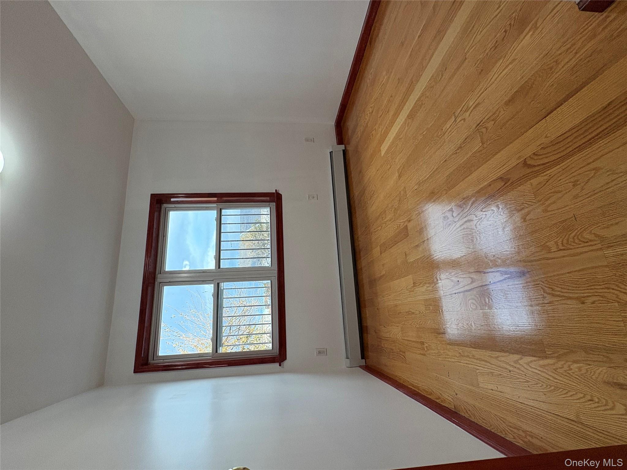 61-40 148th Street, Unit 2 Queens, NY 11367 - Photo 3 of 9 wooden floor in an empty room with a window