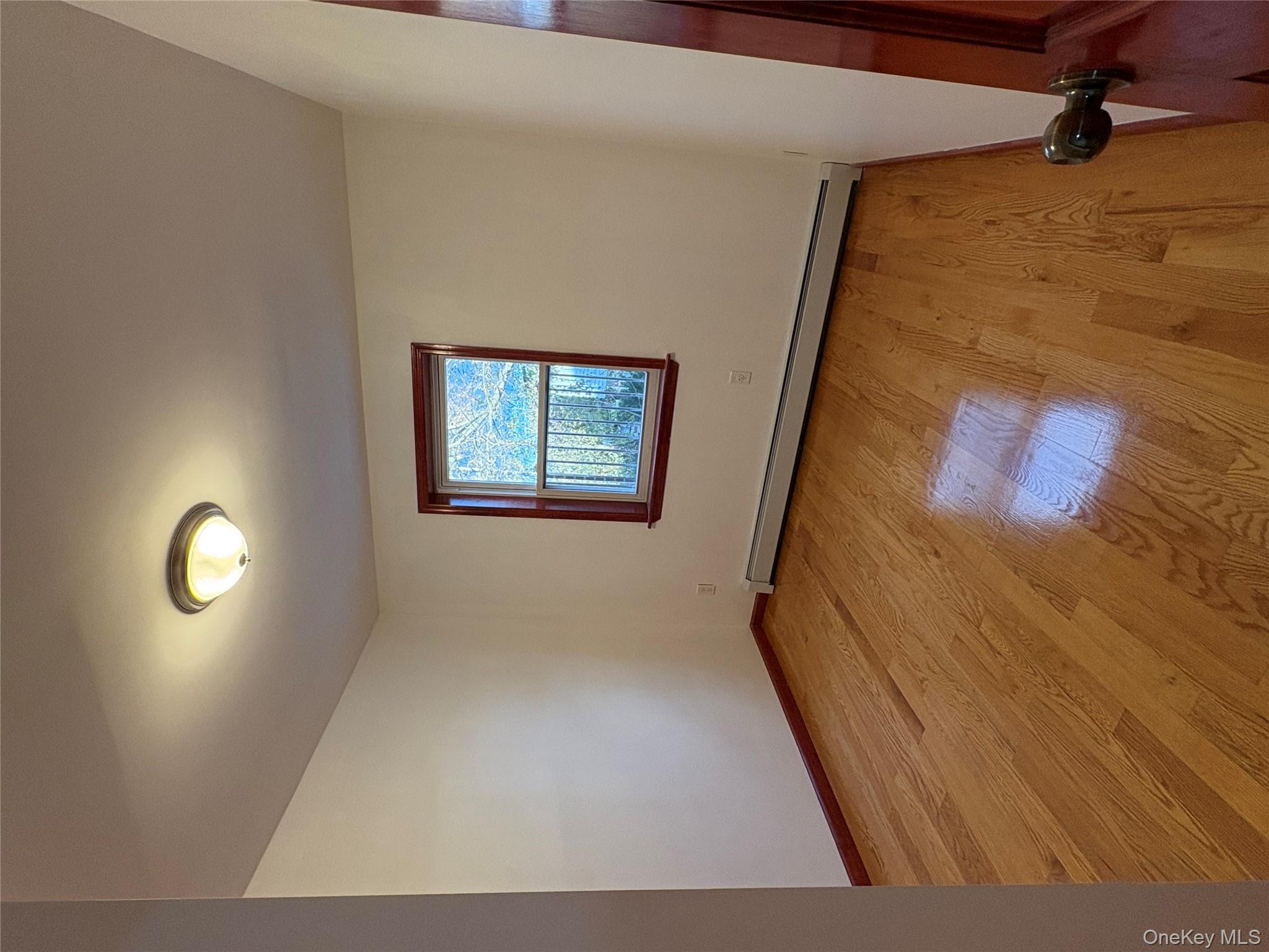 61-40 148th Street, Unit 2 Queens, NY 11367 - Photo 4 of 9 an empty room with wooden floor and windows