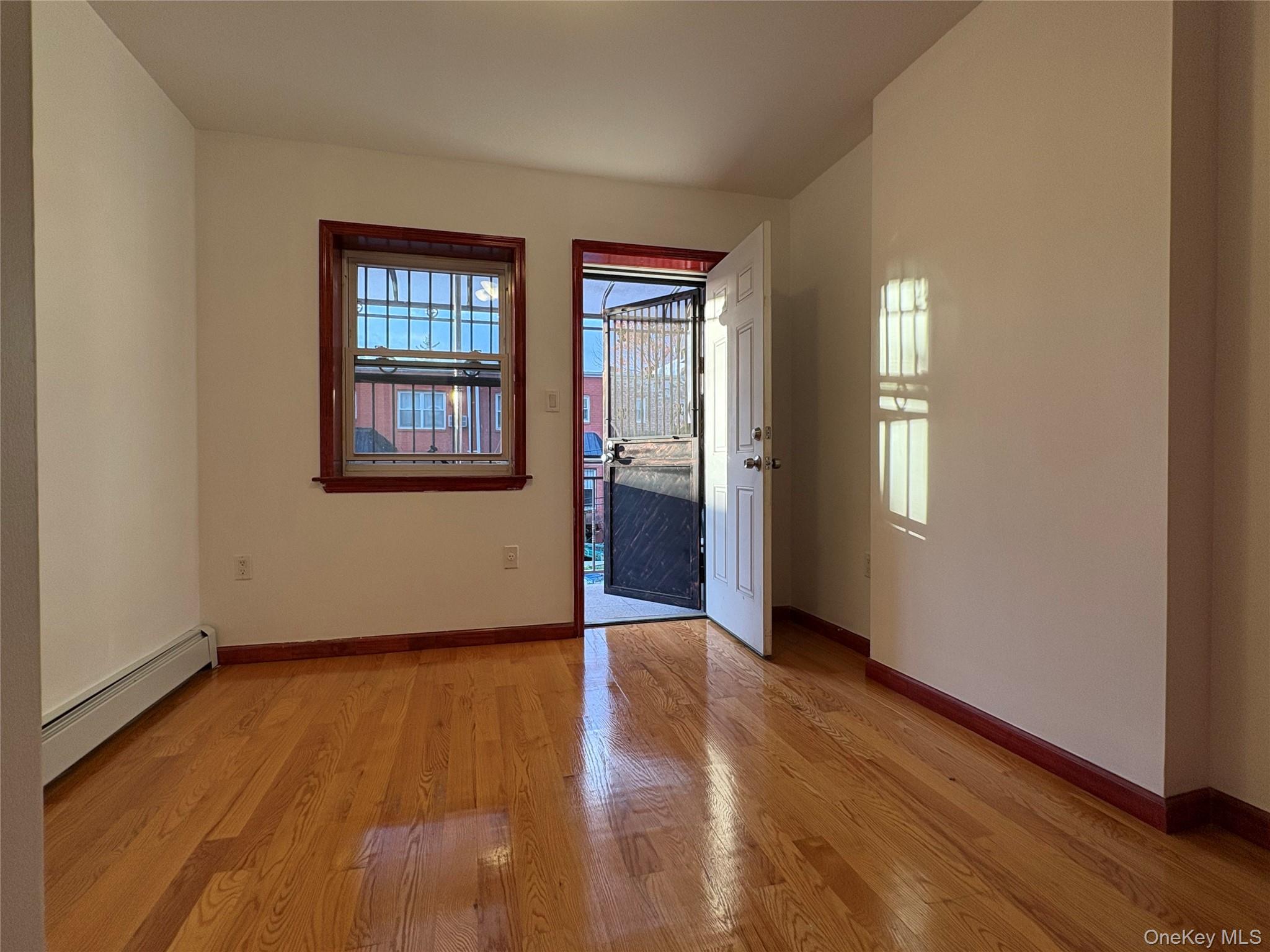 61-40 148th Street, Unit 2 Queens, NY 11367 - Photo 6 of 9 an empty room with wooden floor and windows