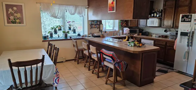 a kitchen with stainless steel appliances granite countertop a table chairs and a refrigerator