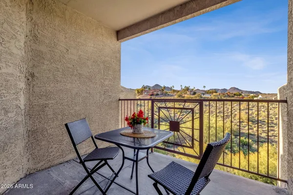a view of a balcony with wooden chairs and city view