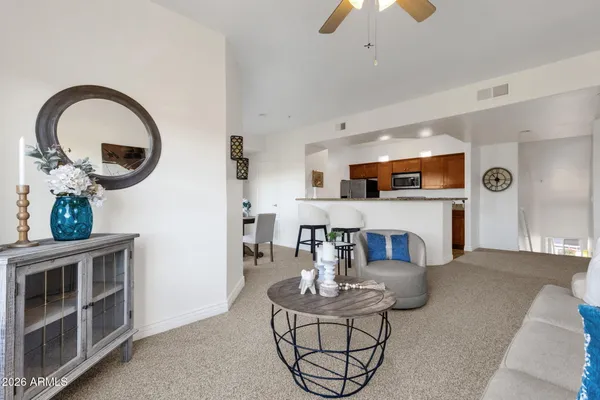 a living room with furniture a table and kitchen view