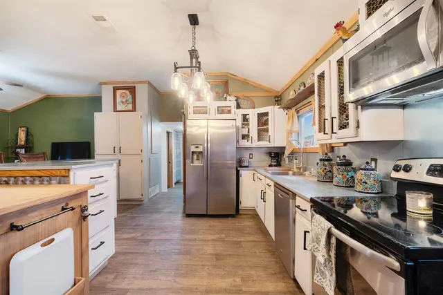 a kitchen with stainless steel appliances granite countertop a lot of counter space and wooden floors