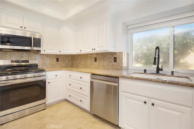 a kitchen with granite countertop white cabinets white stainless steel appliances and a sink