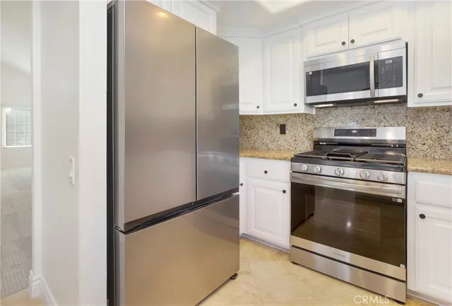 a kitchen with stainless steel appliances white cabinets and a stove top oven
