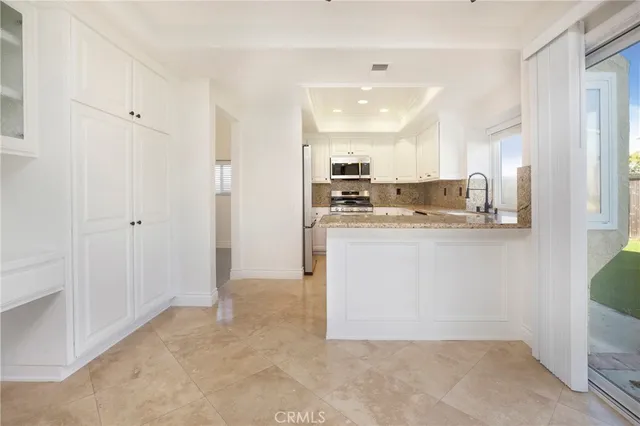 a kitchen with stainless steel appliances granite countertop a refrigerator a sink dishwasher and white cabinets with wooden floor