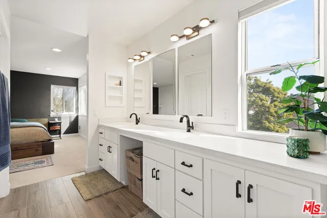 a spacious bathroom with a double vanity sink a mirror a window and vanity