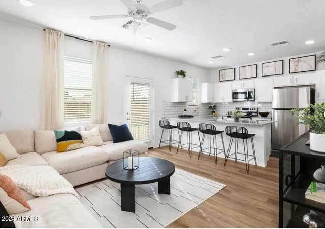 a living room with stainless steel appliances kitchen island granite countertop furniture and a wooden floor