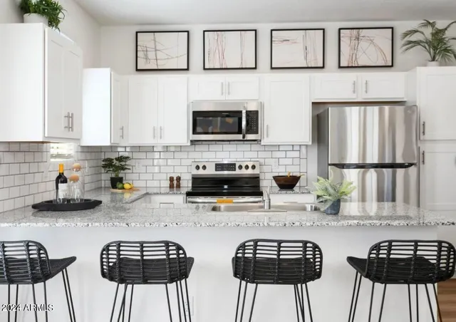 a kitchen with stainless steel appliances kitchen island granite countertop a stove a sink a dining table and chairs