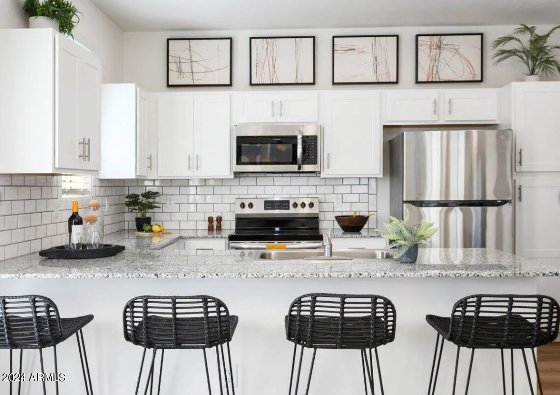 16520 North Greasewood Street, Unit 3 Surprise, AZ 85378 - Photo 5 of 16 a kitchen with stainless steel appliances kitchen island granite countertop a stove a sink a dining table and chairs