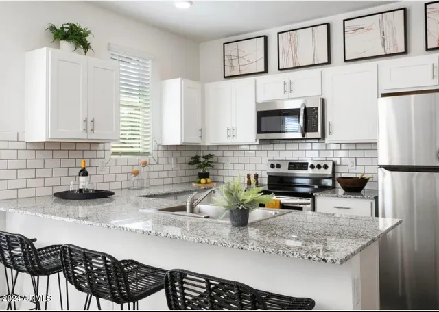 a kitchen with stainless steel appliances granite countertop a sink a stove a microwave a refrigerator and cabinets