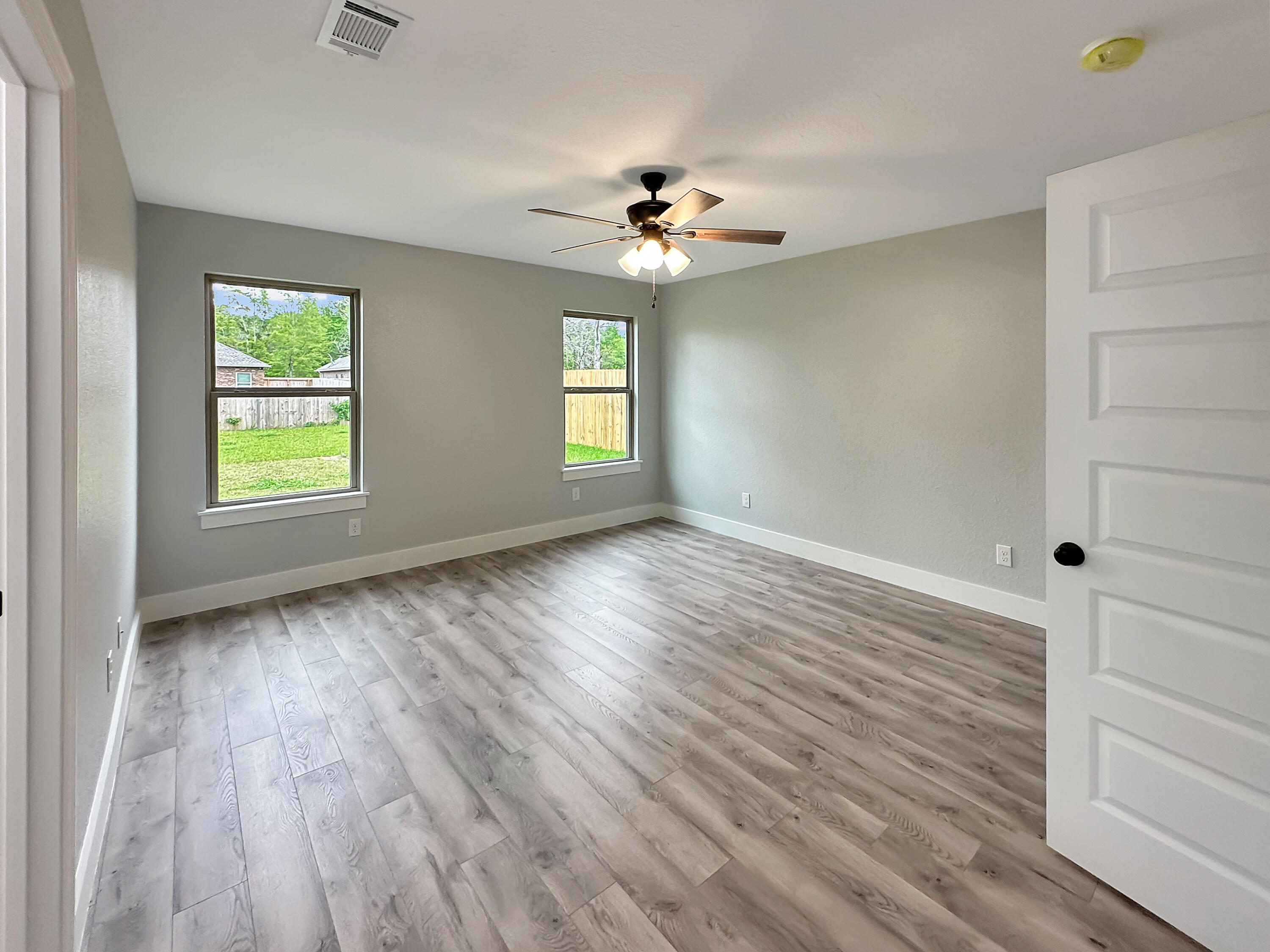 5771 Monroe Street Baker, FL 32531 - Photo 15 of 23 an empty room with wooden floor chandelier fan and windows