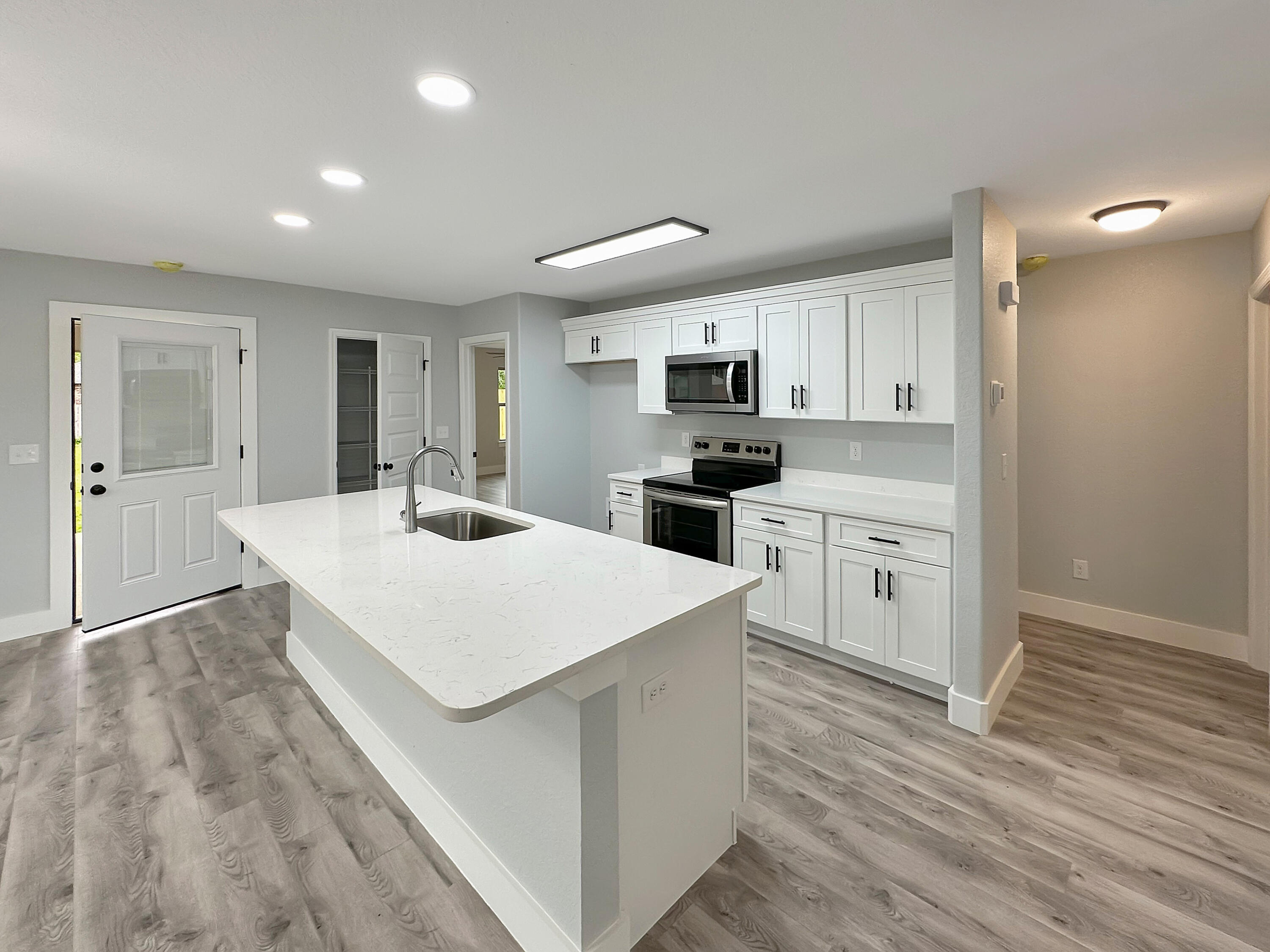 5771 Monroe Street Baker, FL 32531 - Photo 3 of 23 a large white kitchen with kitchen island a sink stainless steel appliances and cabinets