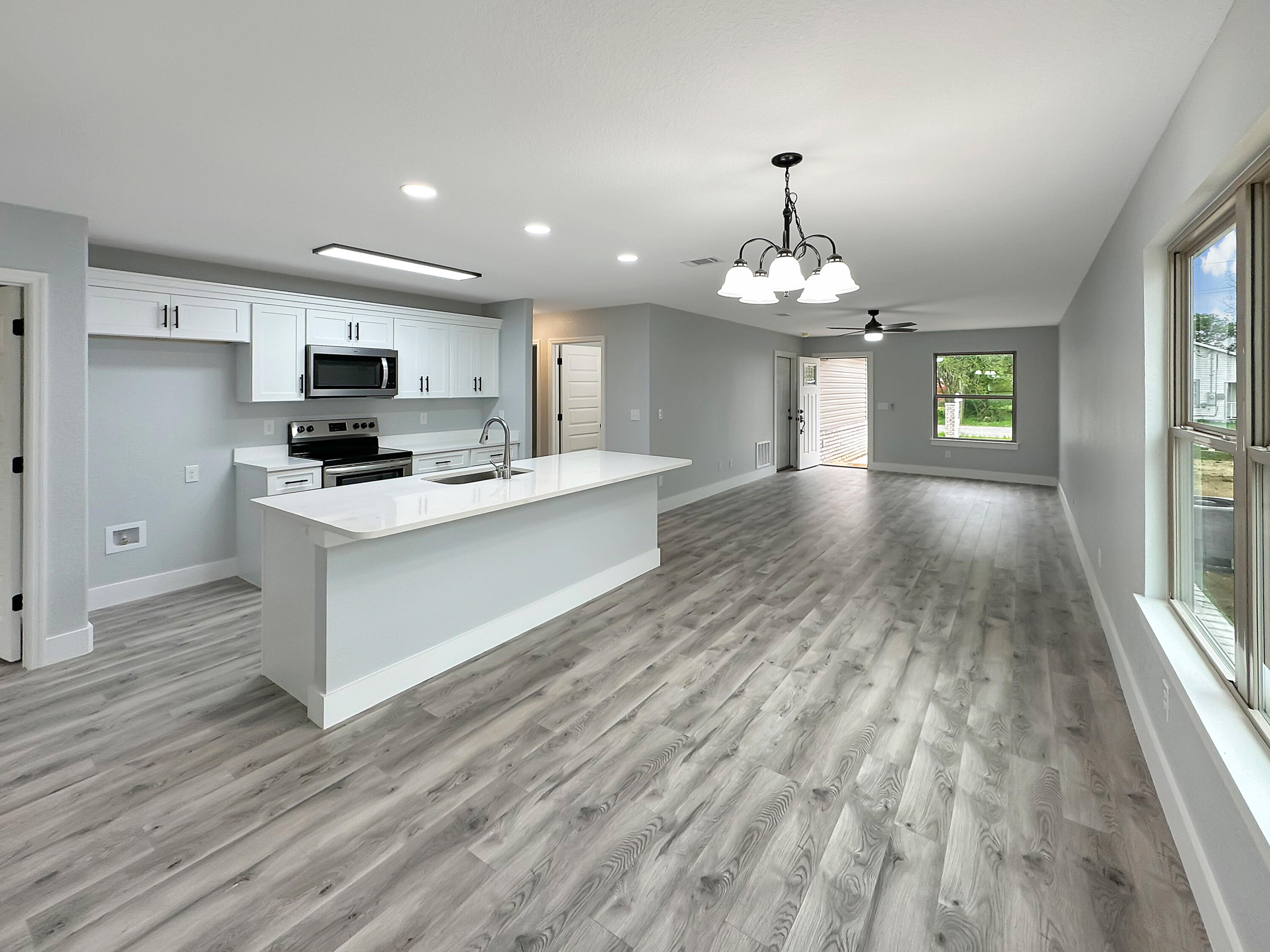5771 Monroe Street Baker, FL 32531 - Photo 8 of 23 a large kitchen with kitchen island a sink dishwasher a refrigerator and a fireplace with wooden floor