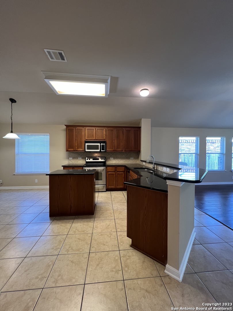 24431 Flint Creek San Antonio, TX 78255 - Photo 13 of 45 a large kitchen with stainless steel appliances a large counter top a stove a sink dishwasher and a refrigerator