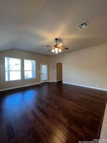 a view of an empty room with wooden floor and a window