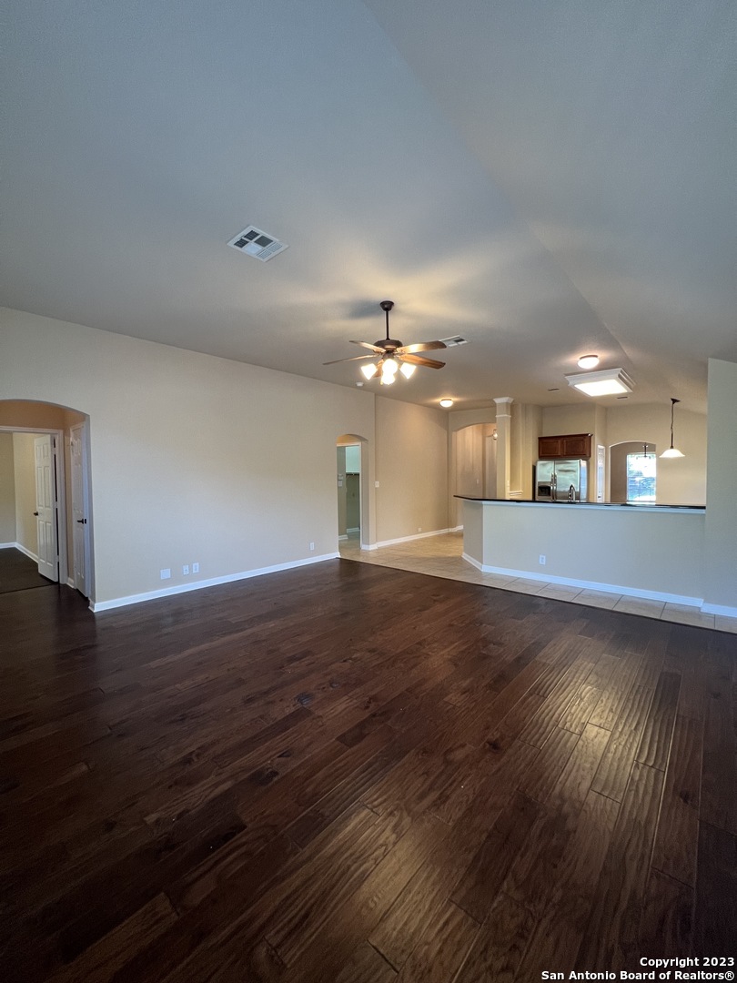 24431 Flint Creek San Antonio, TX 78255 - Photo 16 of 45 a view of an empty room with wooden floor and a kitchen