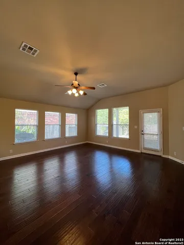 a view of an empty room with wooden floor and a window