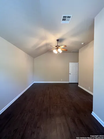 an empty room with wooden floor chandelier fan and windows