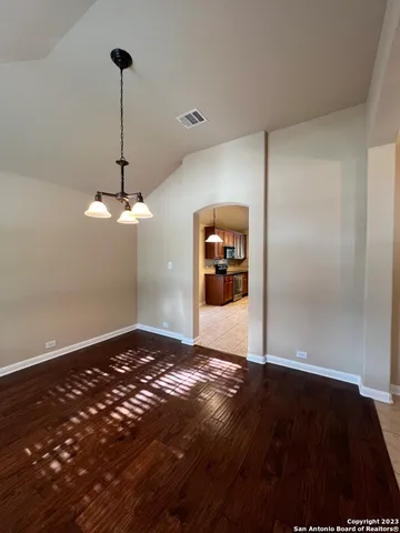 a view of a big room with a chandelier fan and wooden floor