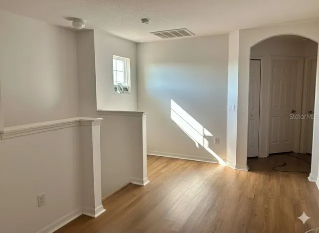 an entryway at an empty room with wooden floor and a window