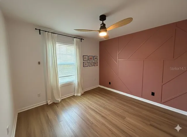 an empty room with wooden floor cabinet and windows